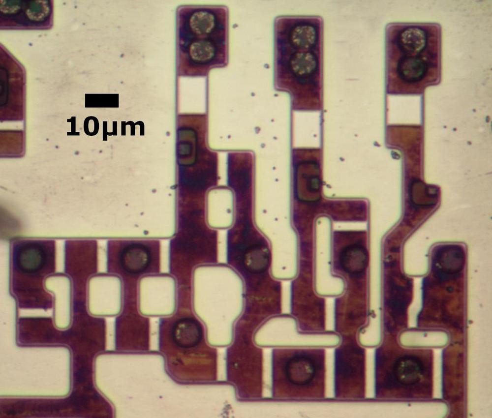 Transistors in the older 8086 chip. The metal and polysilicon were removed for this photo. Circles are vias that connect to the metal layer.