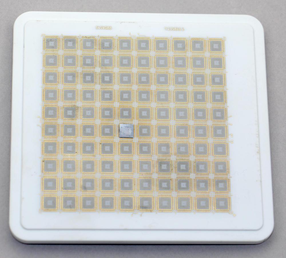 The ceramic substrate for a TCM, from the box. It is fairly small, measuring 11&times11.7 cm. This substrate holds 100 silicon dies; one is visible near the middle.